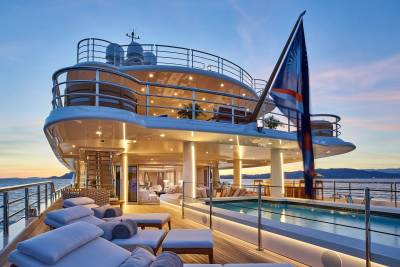 Luxurious loungers and a shimmering pool await on the deck of this opulent yacht at sunset.