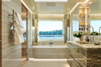 Luxurious marble and warm lighting create a serene spa-like bathroom with a stunning view of the water.
