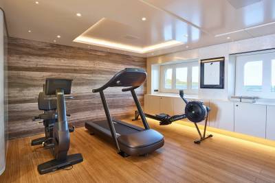 This modern yacht gym offers a treadmill, stationary bike, and rowing machine with ocean views.