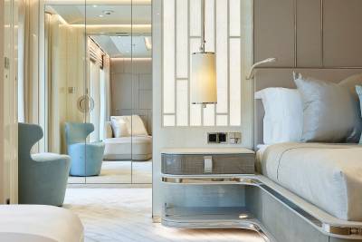 Luxurious bedroom decor features plush seating, mirrored wardrobes, and a stylish bedside table with ambient lighting.