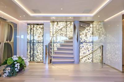 A stunning spiral staircase with illuminated agate walls and polished metal railings creates a luxurious focal point in this elegant interior.