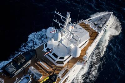 A sleek white yacht cuts through the deep blue ocean, leaving a frothy wake in its path.