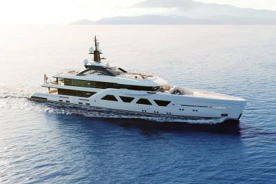 A sleek white superyacht glides through calm blue waters under a hazy sky with distant mountains.