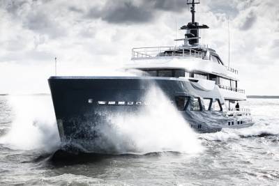 A large, sleek yacht cutting through the choppy waves, with a dramatic cloudy sky in the background.