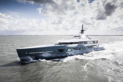 A large, sleek yacht cruising through choppy waters under a dramatic cloudy sky.