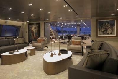 Luxurious yacht interiors offer a sophisticated lounge area with plush seating and captivating artwork overlooking a nighttime seascape.