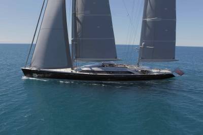 A majestic sailing yacht glides through the tranquil blue ocean under a clear sky.