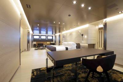 Luxurious yacht interiors feature a spacious bedroom with a modern desk and a cozy seating area.