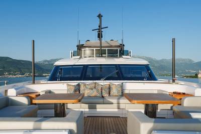 Luxurious seating and dining areas on a modern yacht offer a perfect vantage point for enjoying the scenic coastal landscape.