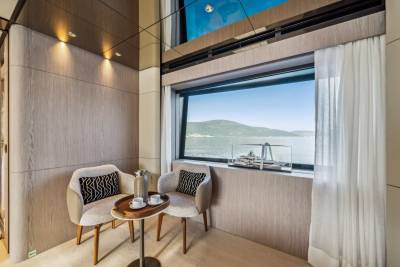 Two chairs and a small table with coffee service offer a cozy spot to enjoy the stunning ocean view from this luxurious interior.