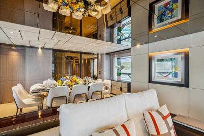 A formal dining table set with flowers and place settings is reflected in the mirrored ceiling of this luxurious yacht interior.