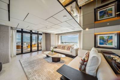 Luxurious yacht interiors offer breathtaking views of a serene coastal landscape through expansive windows.