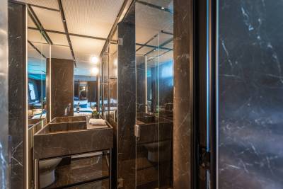 Luxurious dark marble adorns this modern bathroom with a sleek double sink and a glass-enclosed shower.