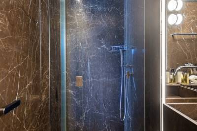 Luxurious dark marble envelops this modern shower stall, creating a sophisticated and spa-like experience.