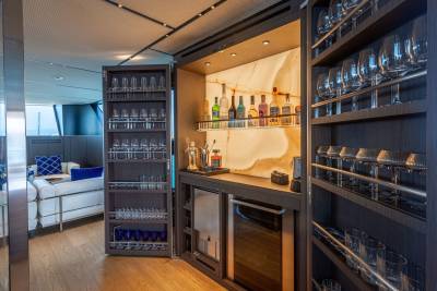 A well-stocked bar with an illuminated onyx backsplash and extensive glassware collection awaits guests.