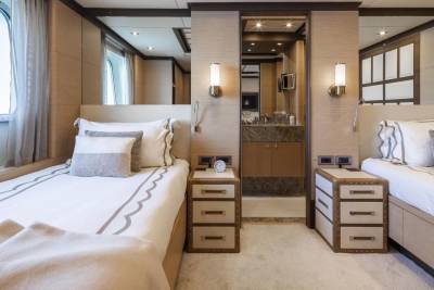Luxurious twin beds flank a marble-accented bathroom, offering a serene retreat on this elegant yacht.
