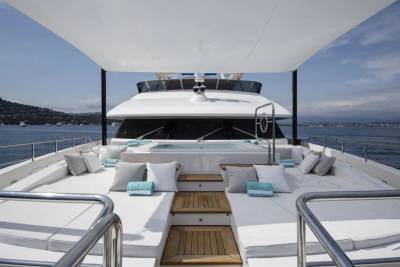Luxurious white cushions and a steaming hot tub await relaxation on the expansive deck of this elegant yacht.