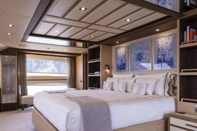 Luxurious yacht accommodations feature a plush king-sized bed adorned with crisp white linens and decorative pillows, overlooking a scenic ocean view.