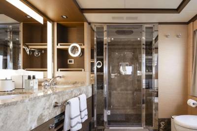 Luxurious yacht bathroom features a marble vanity, glass-enclosed shower, and elegant wood finishes.
