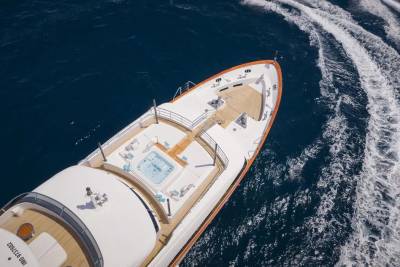 A luxurious yacht glides through deep blue waters, leaving a foamy white wake in its powerful path.