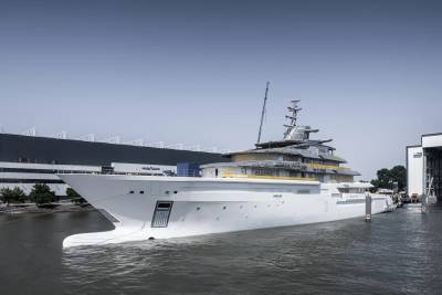 A massive white superyacht named Mercury is docked at a shipyard under a clear blue sky.