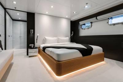 A modern bedroom on a yacht features a plush bed with ambient lighting and a sleek closet.