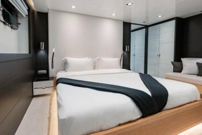 A modern yacht bedroom features a plush king-sized bed, sleek nightstand, and built-in storage for a luxurious nautical escape.