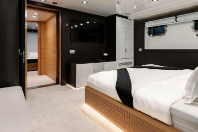 Luxurious yacht cabin features a plush bed, modern entertainment center, and elegant wooden accents.