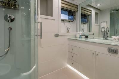 A sleek, modern bathroom features a glass-enclosed shower and a vanity with a glass countertop.