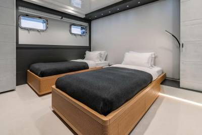 Twin beds with dark grey blankets offer a cozy retreat in this modern yacht cabin.