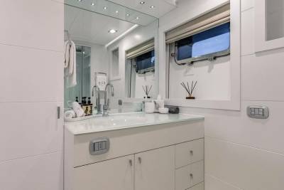 A modern white bathroom features a sleek vanity with a vessel sink and a large mirror reflecting the room's clean lines.