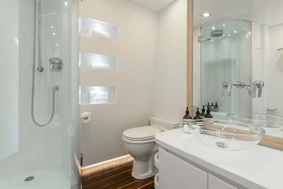 A modern bathroom features a sleek glass shower, a minimalist toilet, and a stylish countertop with two clear vessel sinks.