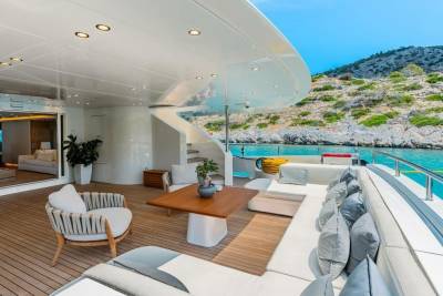 Luxurious yacht deck seating offers a serene spot to enjoy the turquoise waters and rocky coastline.