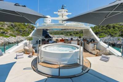 Relax in the bubbling hot tub on the deck of this luxurious yacht, surrounded by stunning coastal scenery.