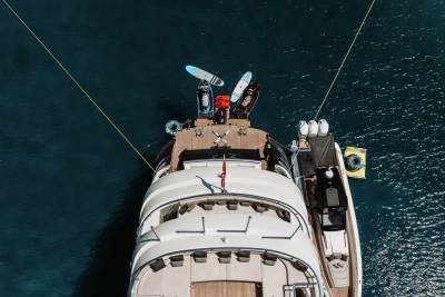 A luxurious yacht floats serenely on the deep blue sea, its deck adorned with water toys and a smaller tender.