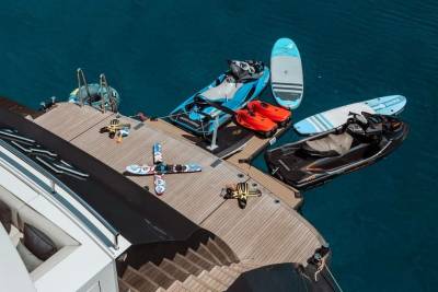 A luxury yacht is equipped with a variety of watercraft, including jet skis and paddleboards, ready for adventure on the open sea.