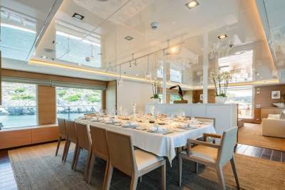 A beautifully set dining table awaits guests aboard this luxurious yacht, offering stunning views of the coastal scenery.