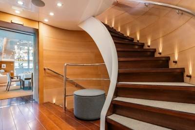 Elegant wooden stairs with subtle lighting lead upwards on this luxurious yacht.