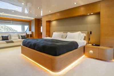 Luxurious yacht cabin features a king-sized bed with ambient lighting and a scenic ocean view.