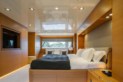 Luxurious yacht interiors feature warm wood paneling and a plush king-sized bed with a scenic view.