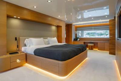 Luxurious yacht bedroom features warm wood accents, a plush bed, and ambient lighting for ultimate relaxation.