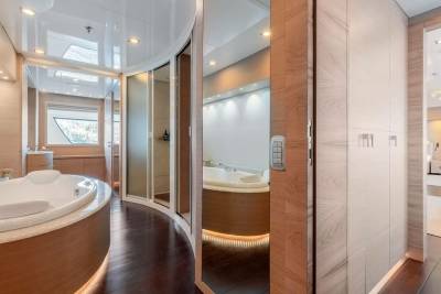 Luxurious yacht bathroom features a spacious jacuzzi, sleek shower, and elegant wood and marble finishes.