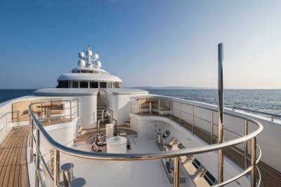 The sun glints off the polished chrome railings of this luxurious yacht as it cruises through calm, blue waters.