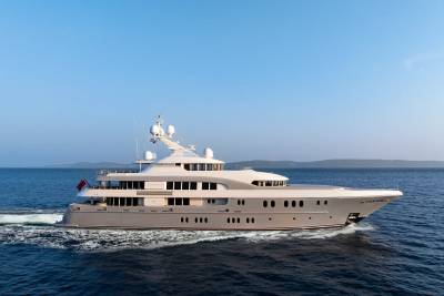 A sleek, modern yacht glides through calm blue waters under a clear sky.