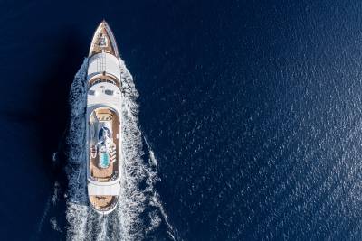 A luxurious yacht glides through the deep blue ocean, leaving a foamy white wake behind it.