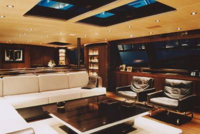 Luxurious yacht interiors feature plush seating, a rich wooden coffee table, and skylights illuminating the elegant lounge.