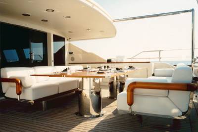 A beautifully set dining table awaits on the deck of a luxurious yacht, surrounded by comfortable white seating.