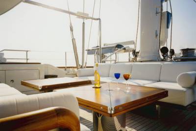 Two wine glasses and a bottle of white wine await guests on a yacht's polished wooden deck.