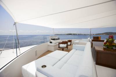 Relax on the plush white seating of this luxurious yacht, enjoying the stunning ocean views and distant coastline.