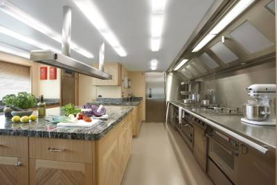 A professional kitchen on a yacht features stainless steel appliances, granite countertops, and fresh produce ready for culinary creations.